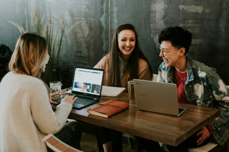 Tre ragazzi che lavorano insieme al computer seduti a un tavolo