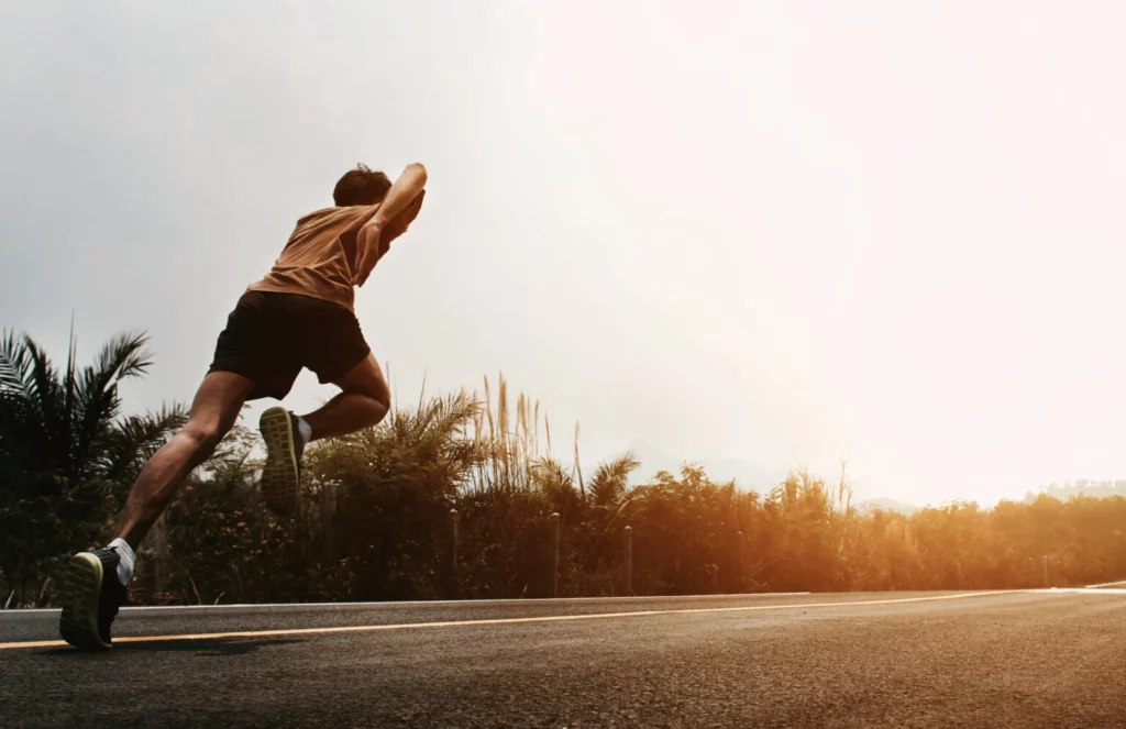 Ragazzo che corre su una strada al tramonto