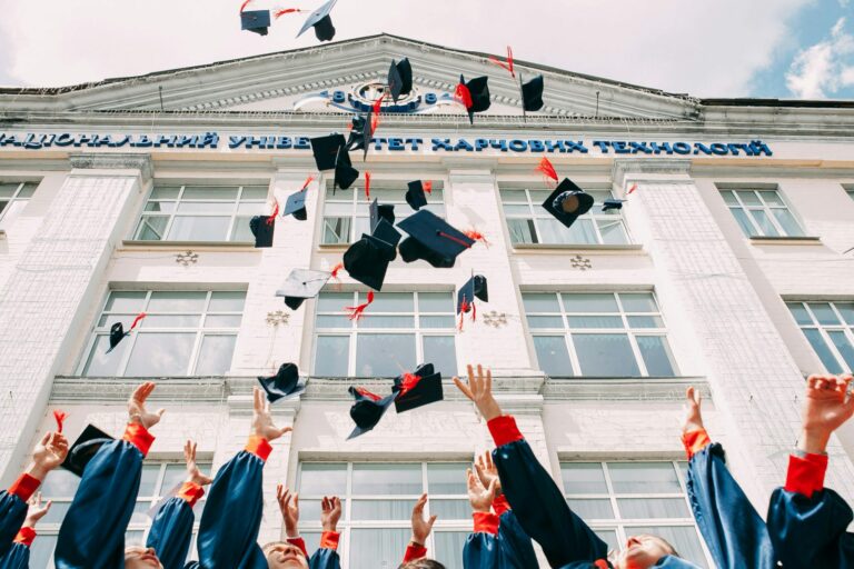Studenti in toga che lanciano il tocco in aria davanti all'università